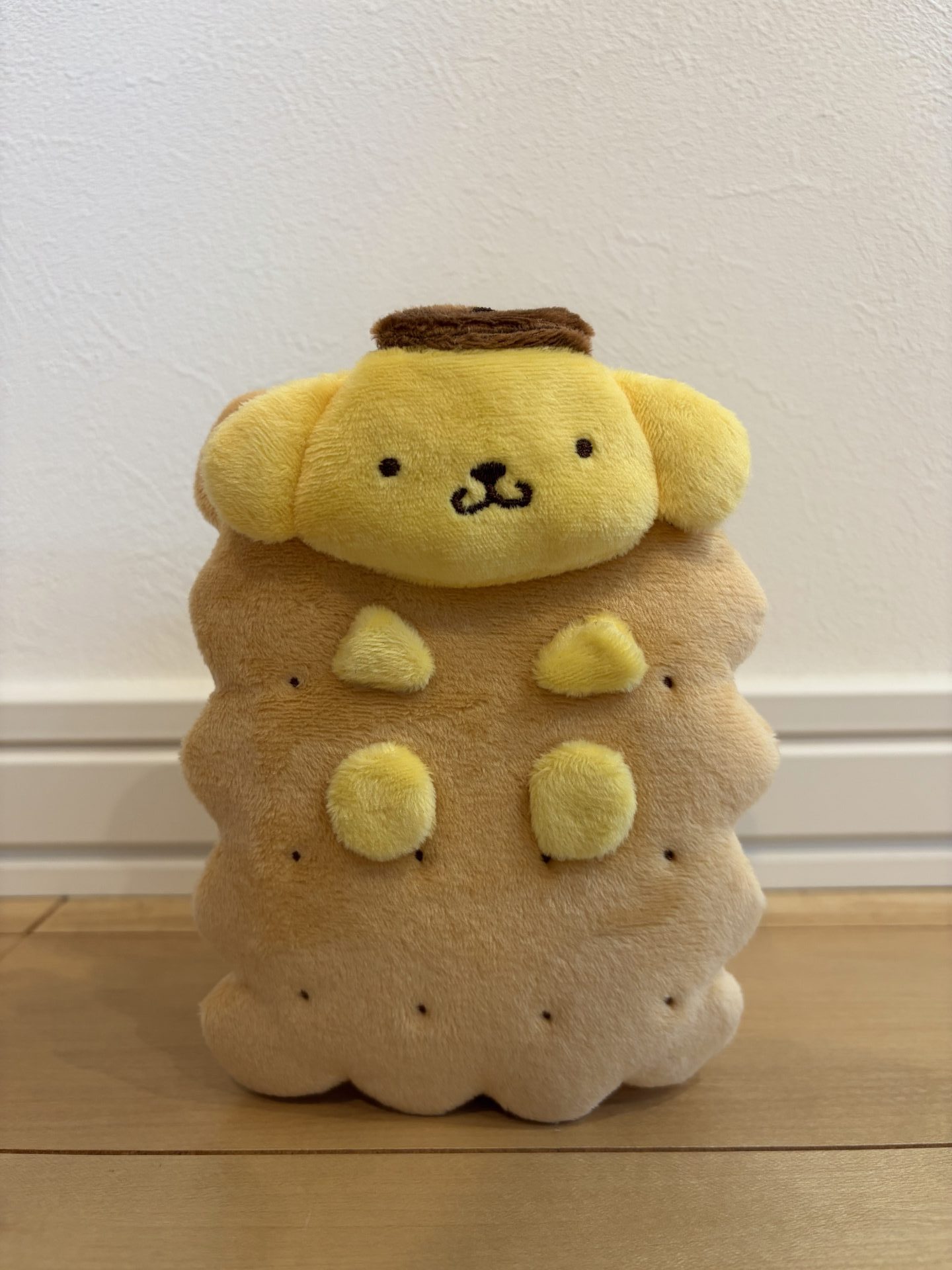 ポムポムプリンがココナッツサブレに挟まったデザインのぬいぐるみポーチ。正面。